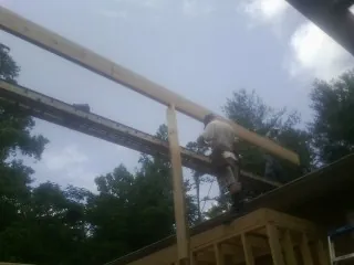 Carpenter setting a ridge beam over a new addition frame — Ice Dam Removal by Roofing Brothers in Locust Grove