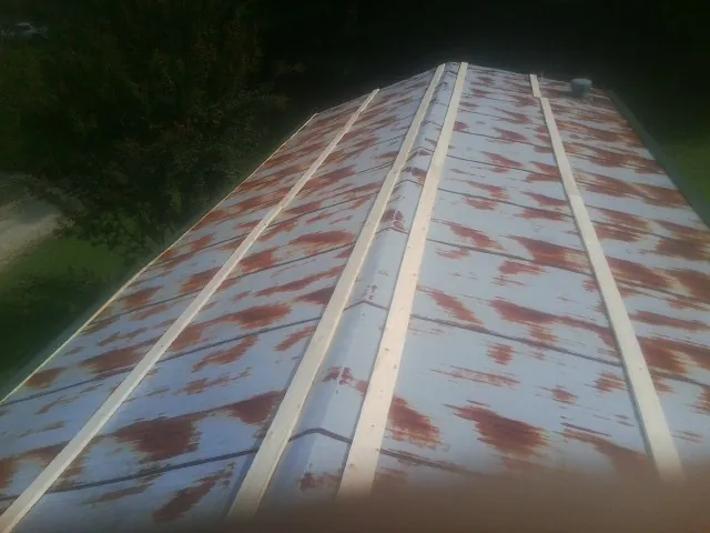 Rusted metal roof panels with new wood purlins before replacement — Storm Damage Roof Repair in Locust Grove by Roofing Brothers
